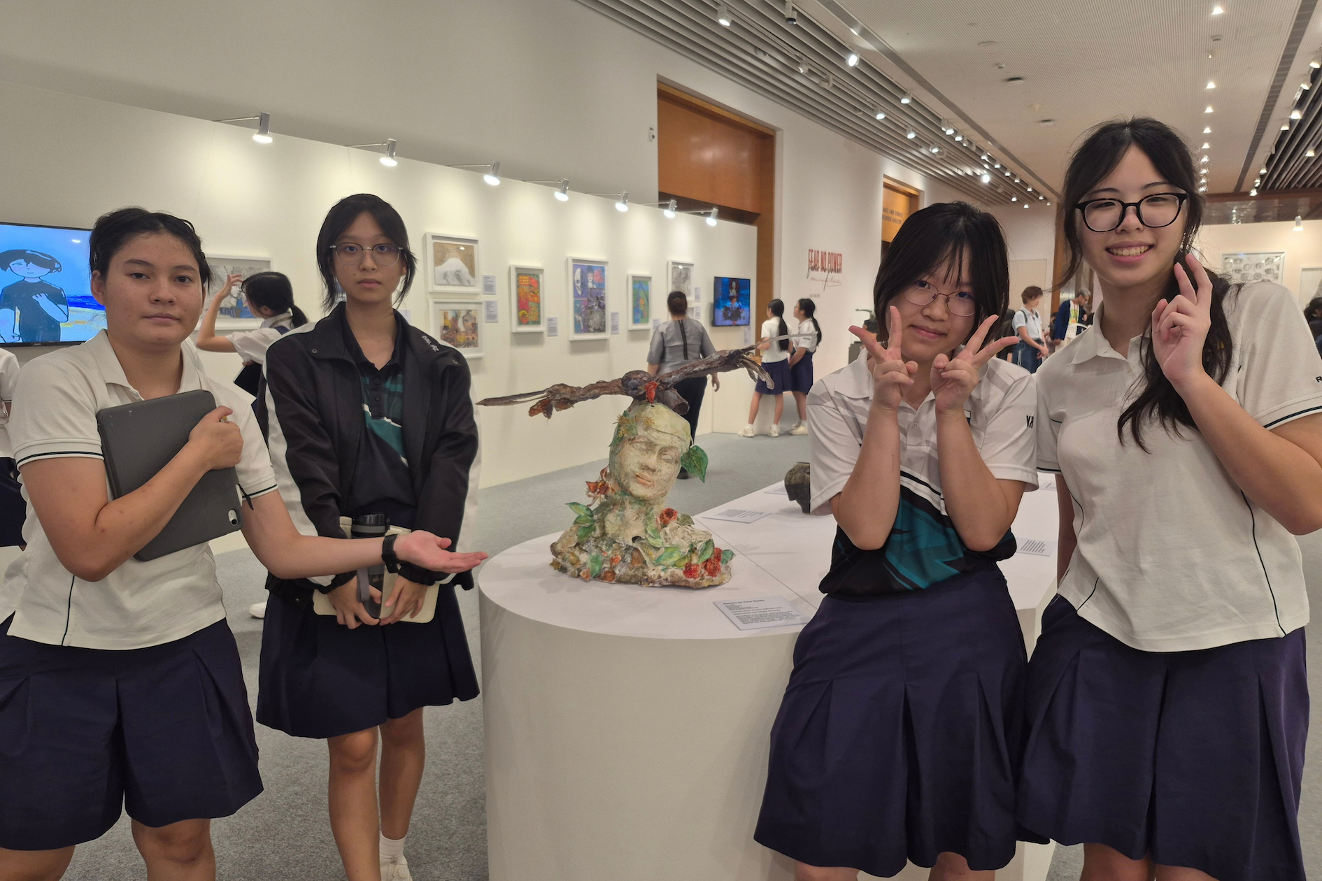 A group of female students posing in front of an artwork in an art gallery.